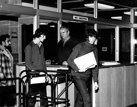 Library staff checking books at the turnstile exit on level three before the installation of electronic security in 1986.
