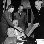 President Roosevelt (seated) and Mrs Roosevelt inspect the facsimile copy of Captain Cook's journal that was presented to Mrs Roosevelt by John Curtin when she visited Australia in 1943. National Library of Australia: MS6923