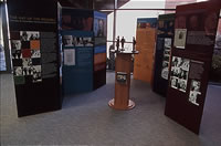 Exhibition with panels arranged on either side of the central plinth and figurines