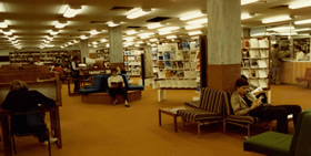 Level five of the Library in the early 1980s showing the microfiche catalogue in use, the current journal area with comfortable lounge style seating and carrels for individual study.