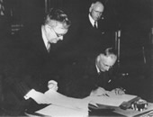 Prime Minister John Curtin (seated) flanked by Minister for External Affairs Dr Evatt (left) and New Zealand Prime Minister Peter Fraser signs the Anzac Agreement. MacArthur Memorial Library and Archives: MML&A 20082.