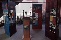 Exhibition with 3 groups of 3 panels arranged around the central plinth and figurines
