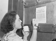 Parliament House staff implementing war precautions - fixing evacuation procedures to teh back of a door, 1942