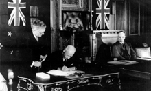 NZ PM Peter Fraser signing the ANZAAC Agreement watched by H.V. Evatt, John Curtin in the background. 21 January 1944. JCPML00018/21.